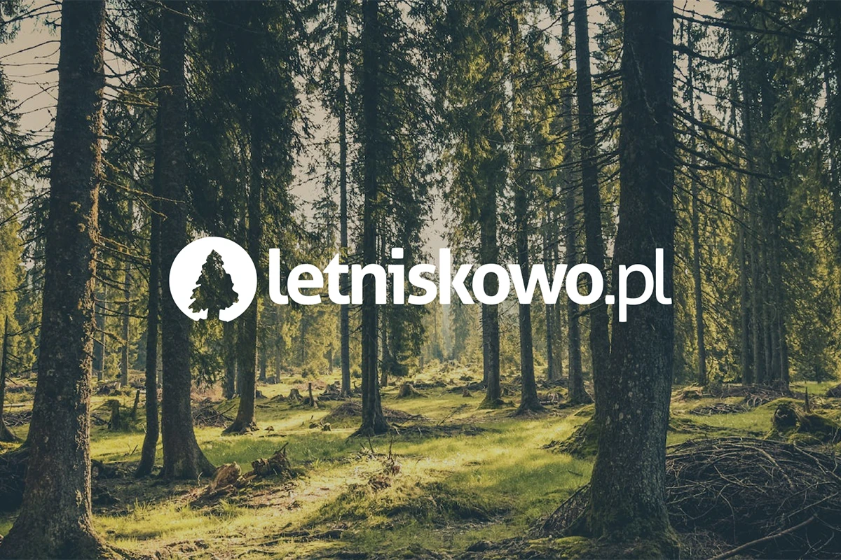 Logo letniskowo.pl osadzone na tle lasu. Symbolika drzewa w okręgu podkreśla związki z naturą i wypoczynkiem na łonie przyrody, sugerując ekologiczną markę.